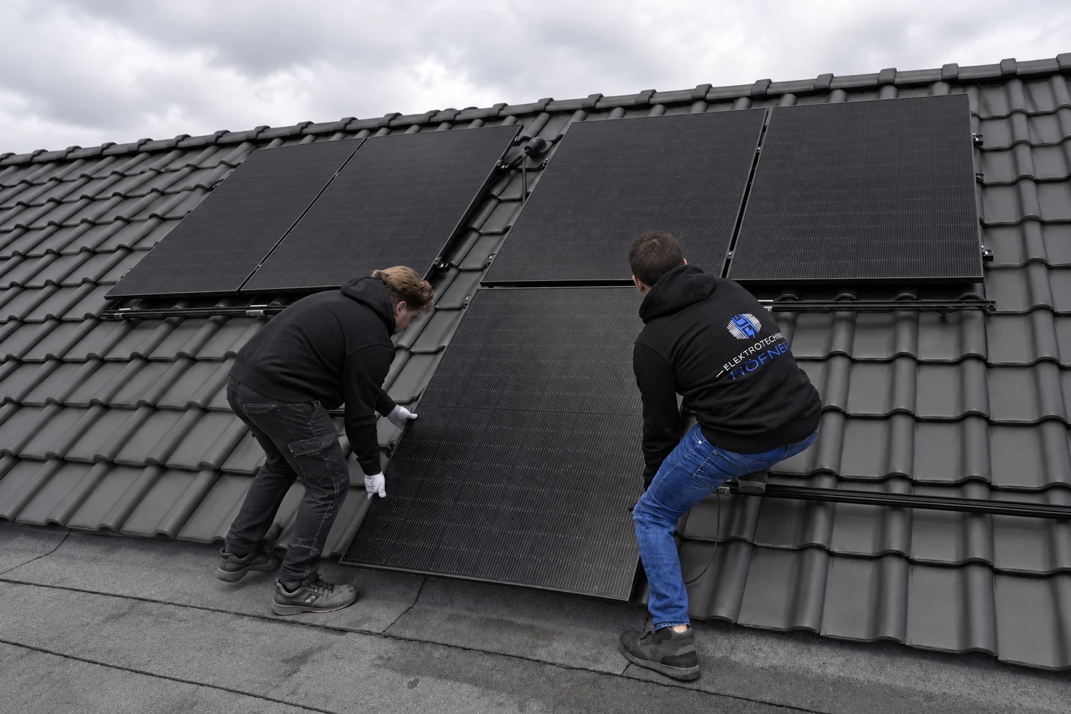 Mitarbeiter mit Photovoltaikmodulen auf einem Dach – KI-bearbeitete Bildfassung